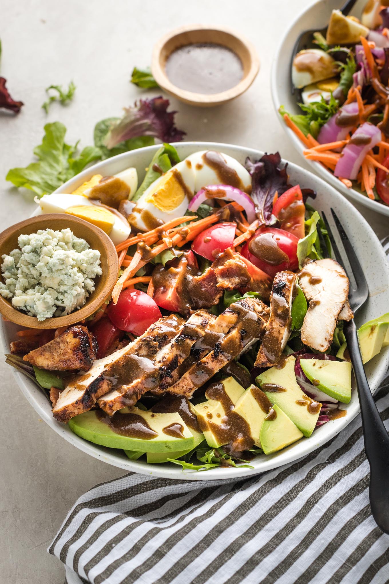 Cobb salads in white bowls served with grilled chicken and balsamic vinaigrette.