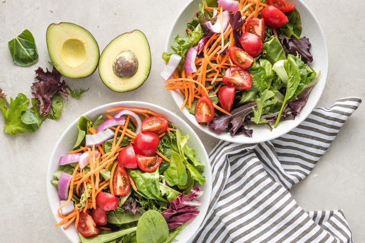 Greens, carrots, and cucumber in bowls.