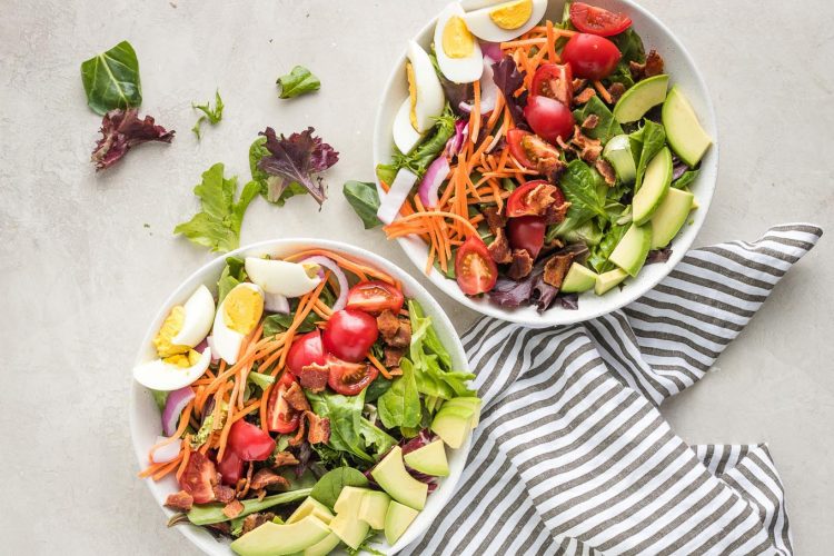 Salad bowls with hard-boiled eggs and avocado added.