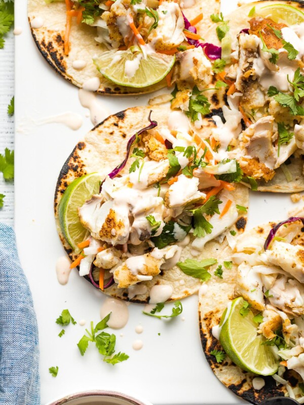 Platter with fish tacos served with slaw and adobo crema.