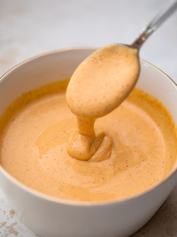 spoon dipping into a white bowl full of yum yum sauce