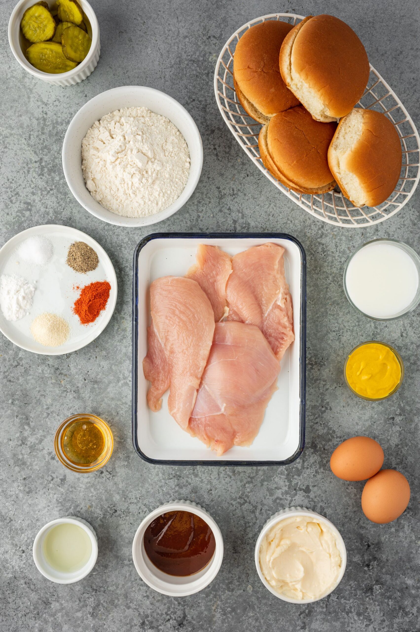 Raw chicken breasts with seasonings and flour divided into small bowls.