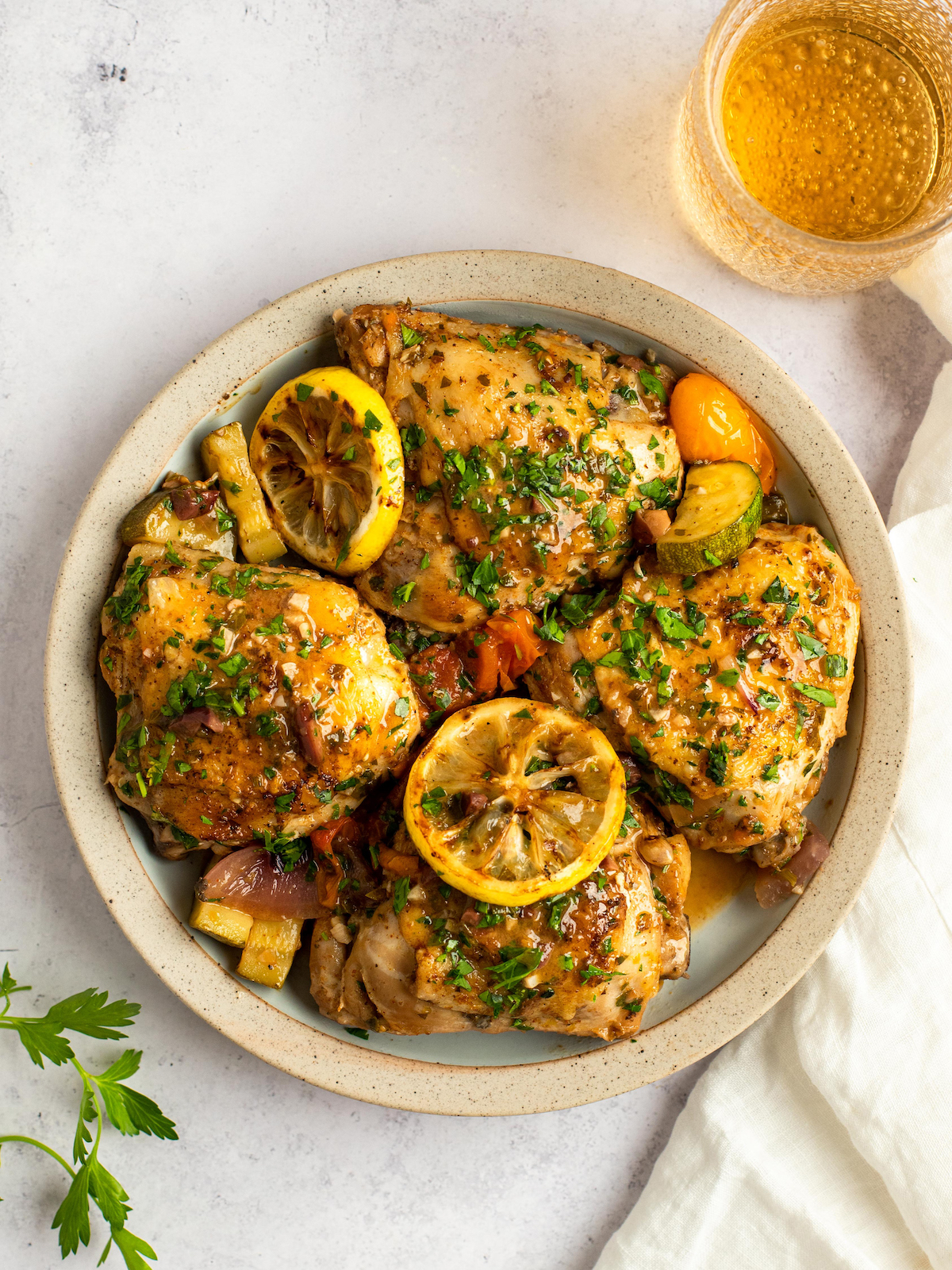 Chicken thighs with sauce and veggies on a white plate.