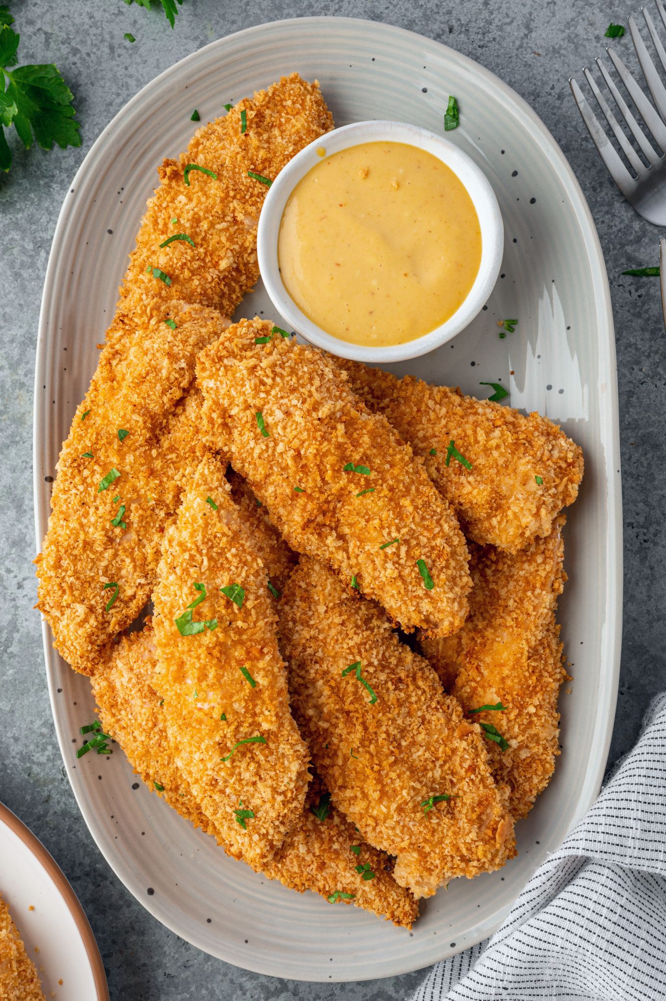Crispy chicken tenders on a plate with honey mustard.