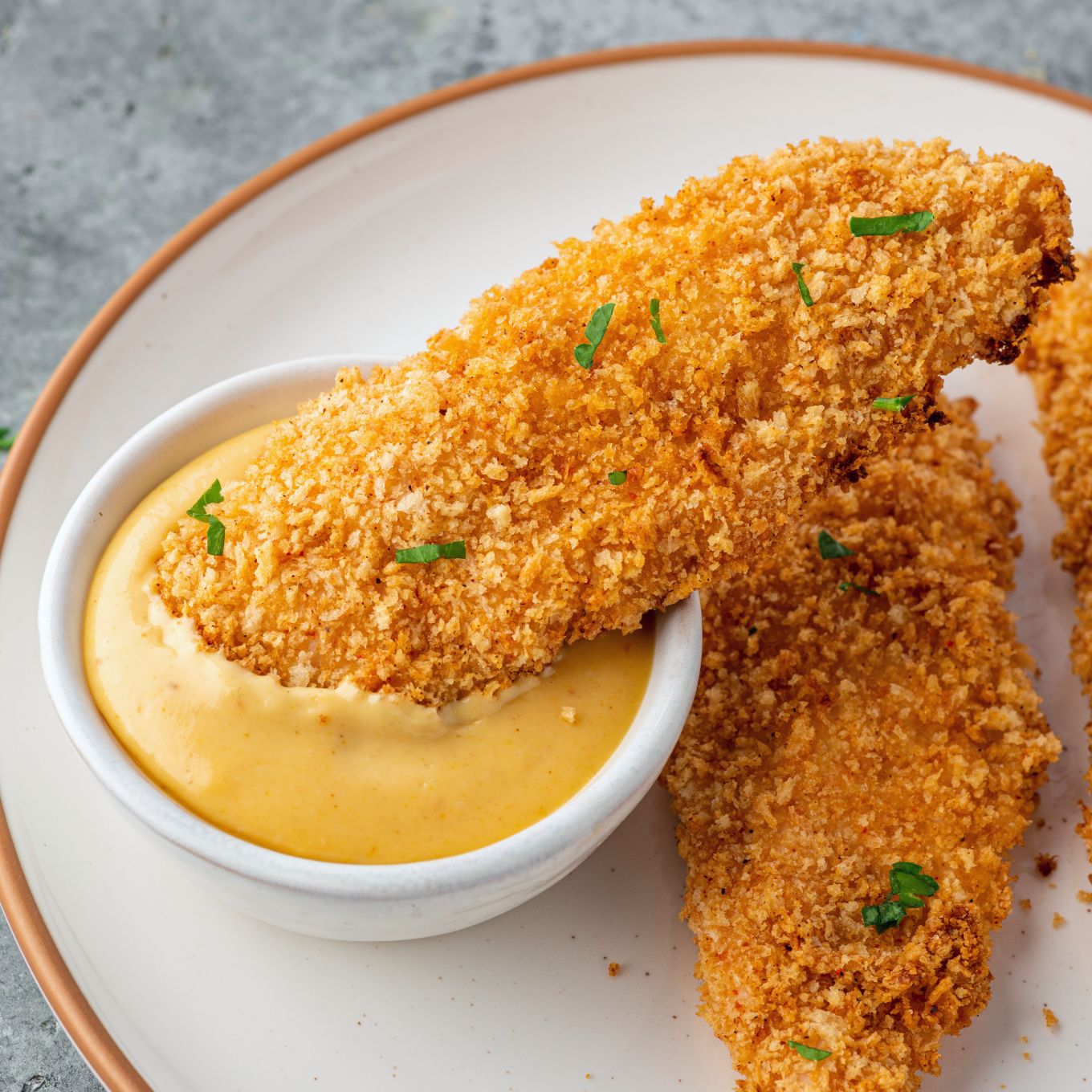 Crispy chicken tender dipped into honey mustard.