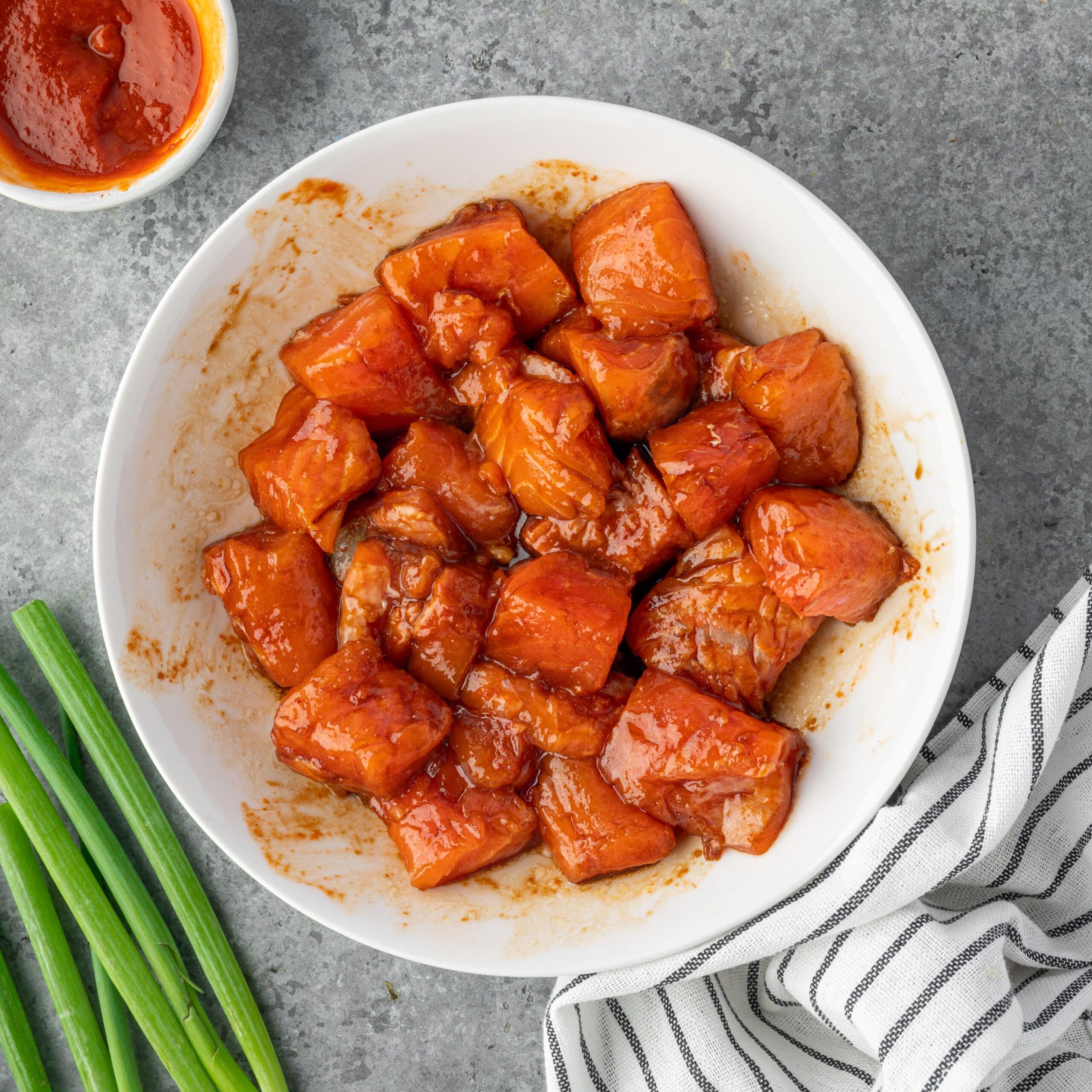 Marinating chopped salmon in a white bowl.