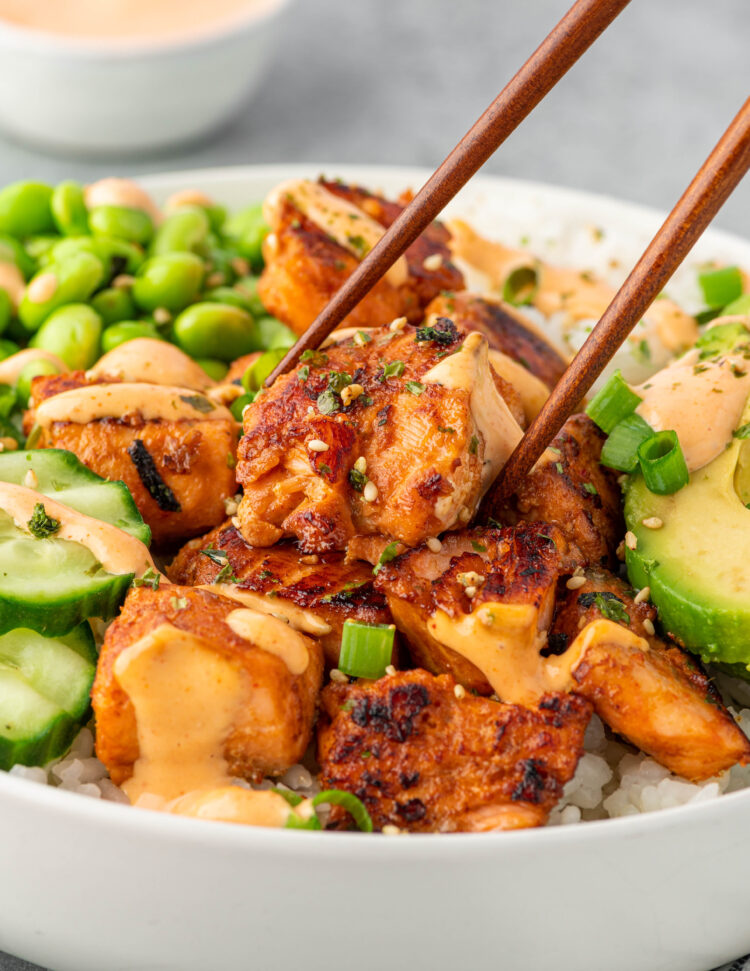 Picking up a piece of salmon with chopsticks.