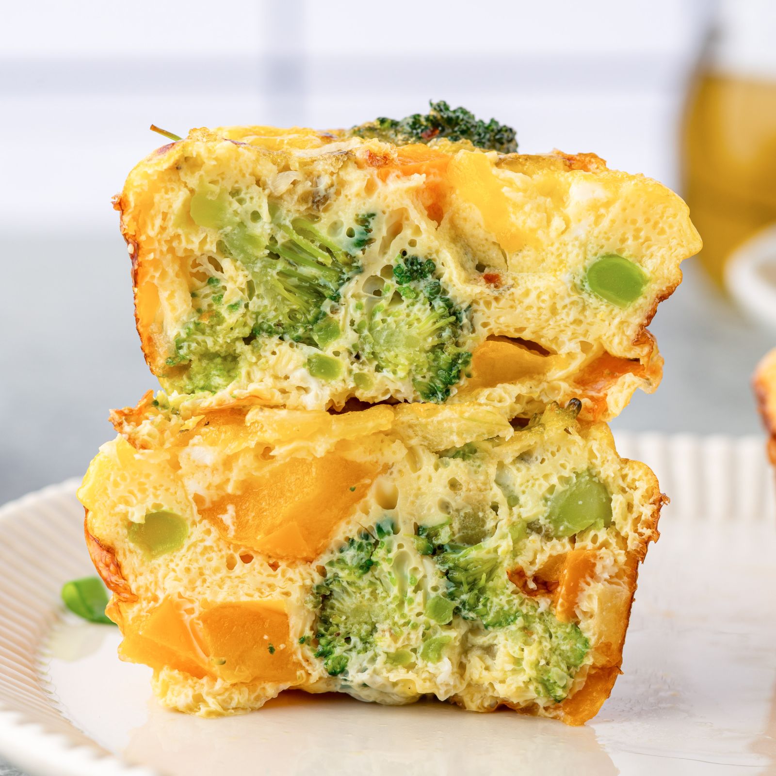An egg muffin cut into with broccoli and bell pepper.