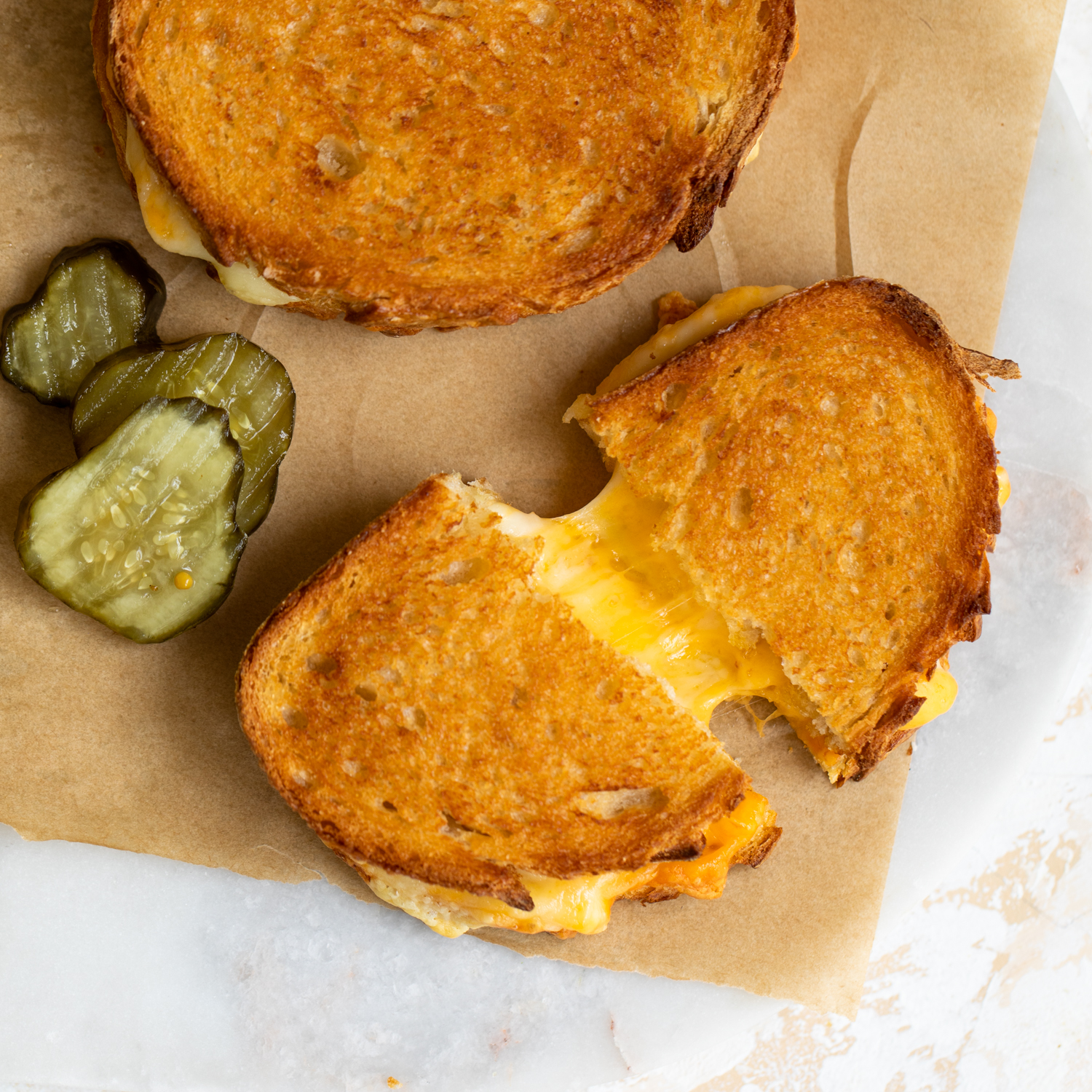 Cheesy grilled cheese sandwich on parchment paper.