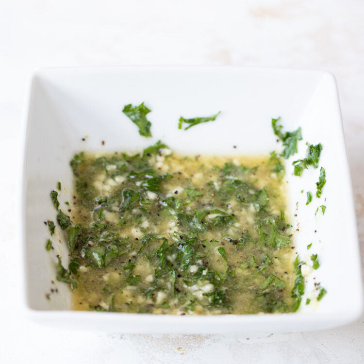 Lemon, butter and parsley mixed in white bowl.