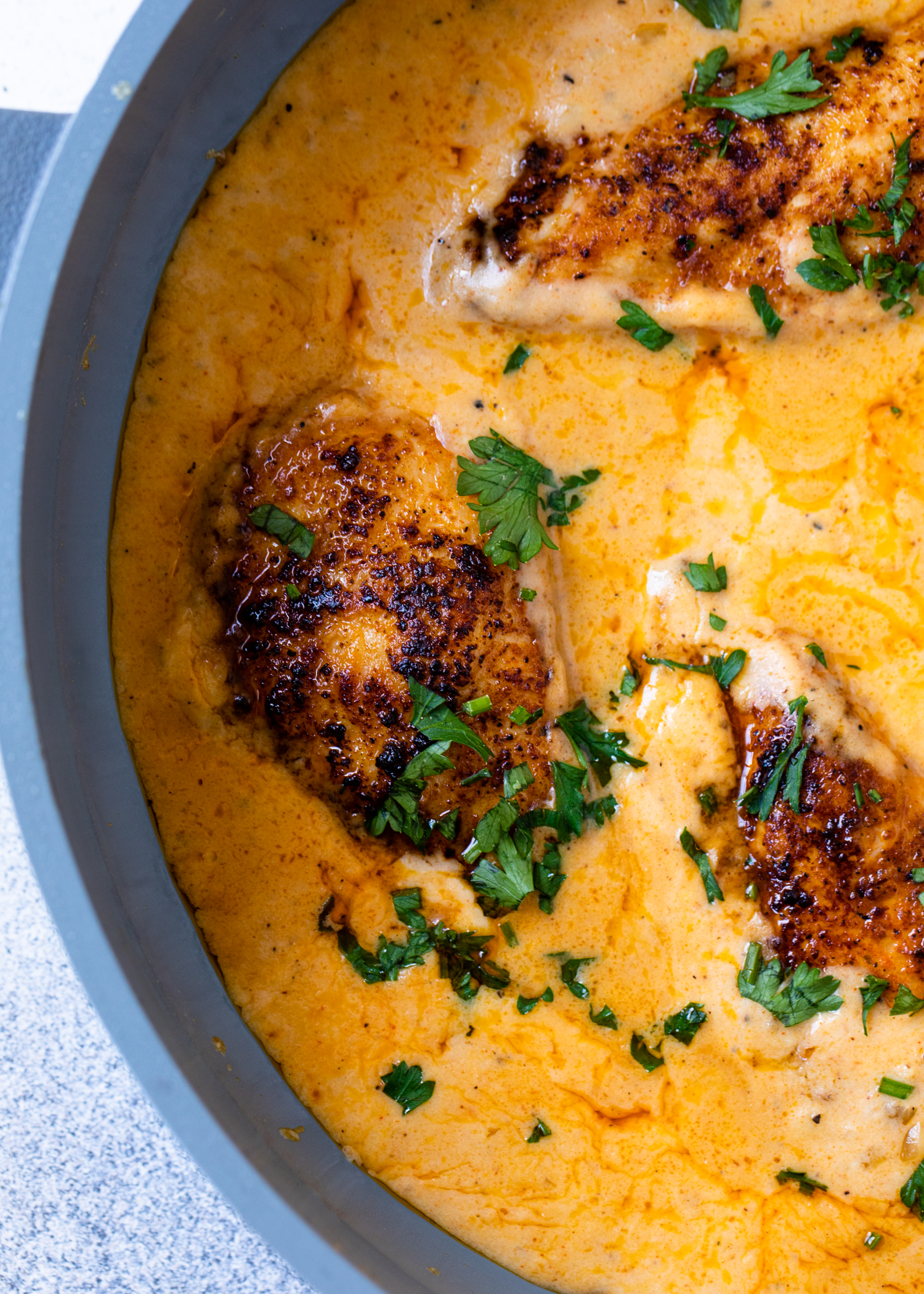Creamy cajun chicken garnished with fresh parsley in a large pan.