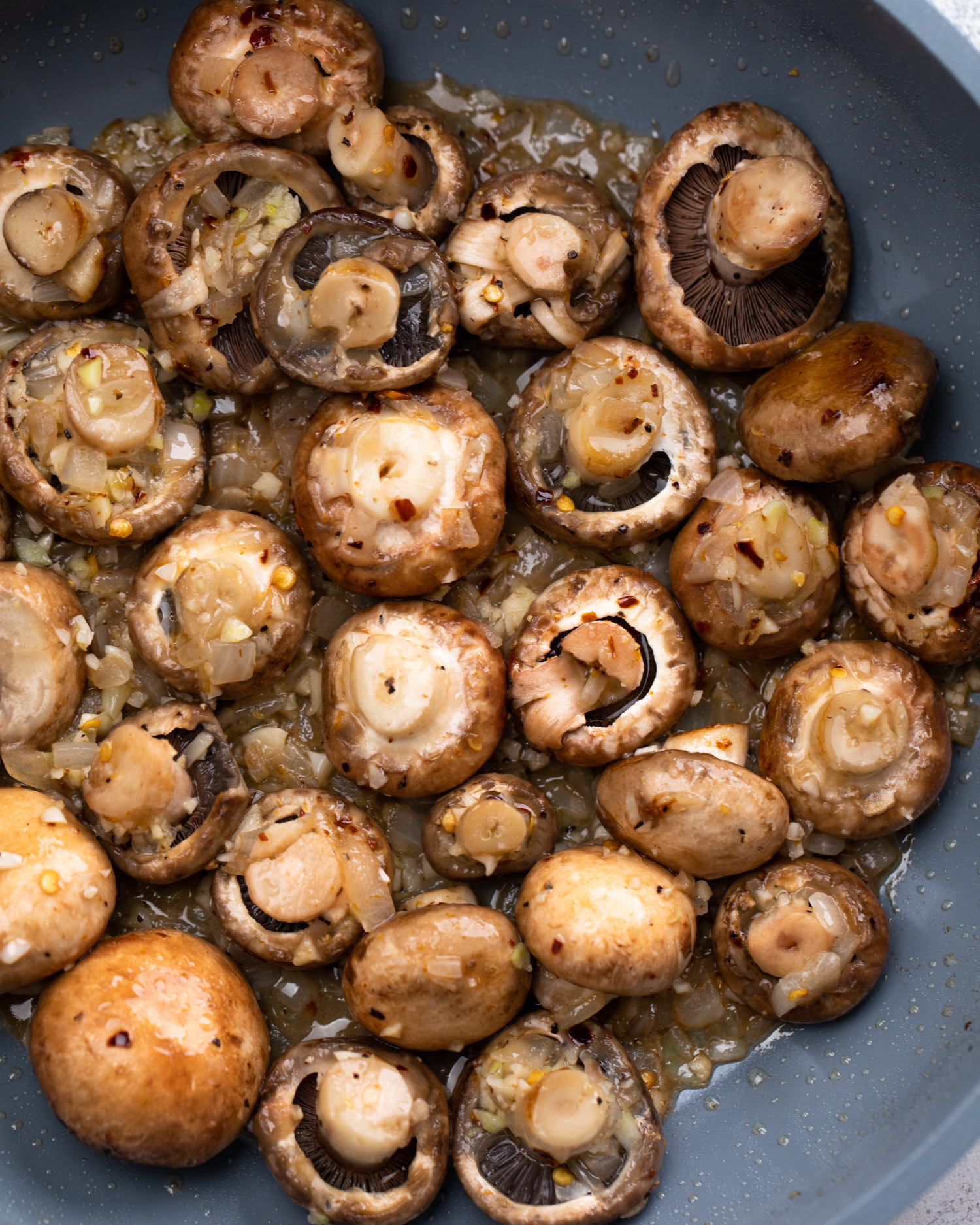 Mushrooms sautéing in a skillet.