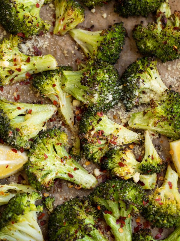 Roasted broccoli on a pan with lemon wedges.