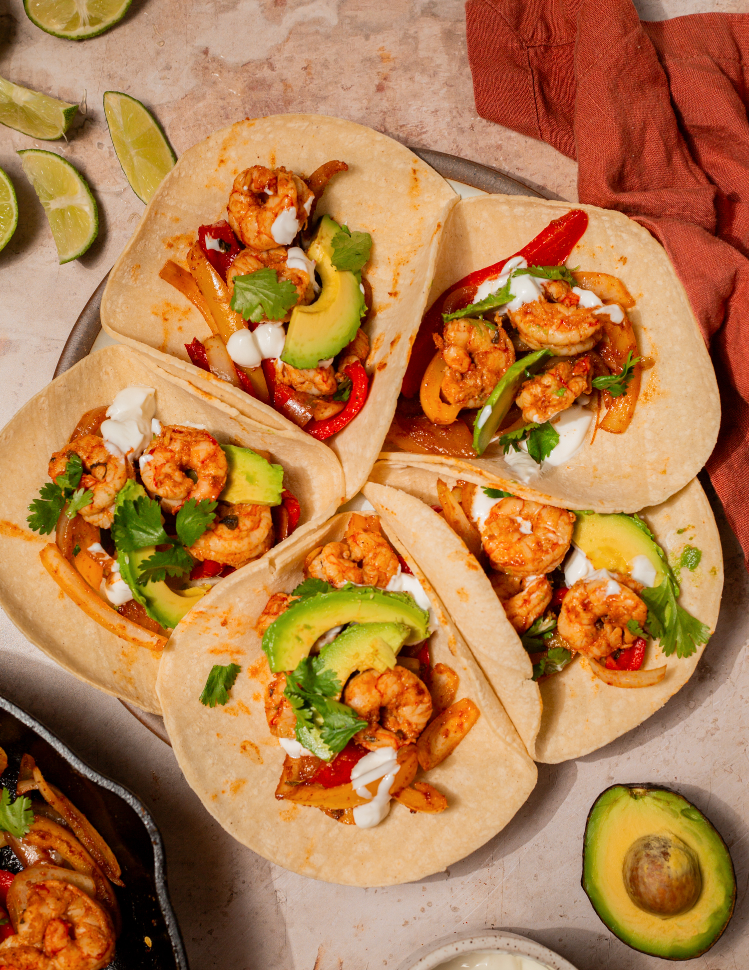 Shrimp fajitas in tortillas with sliced avocado.