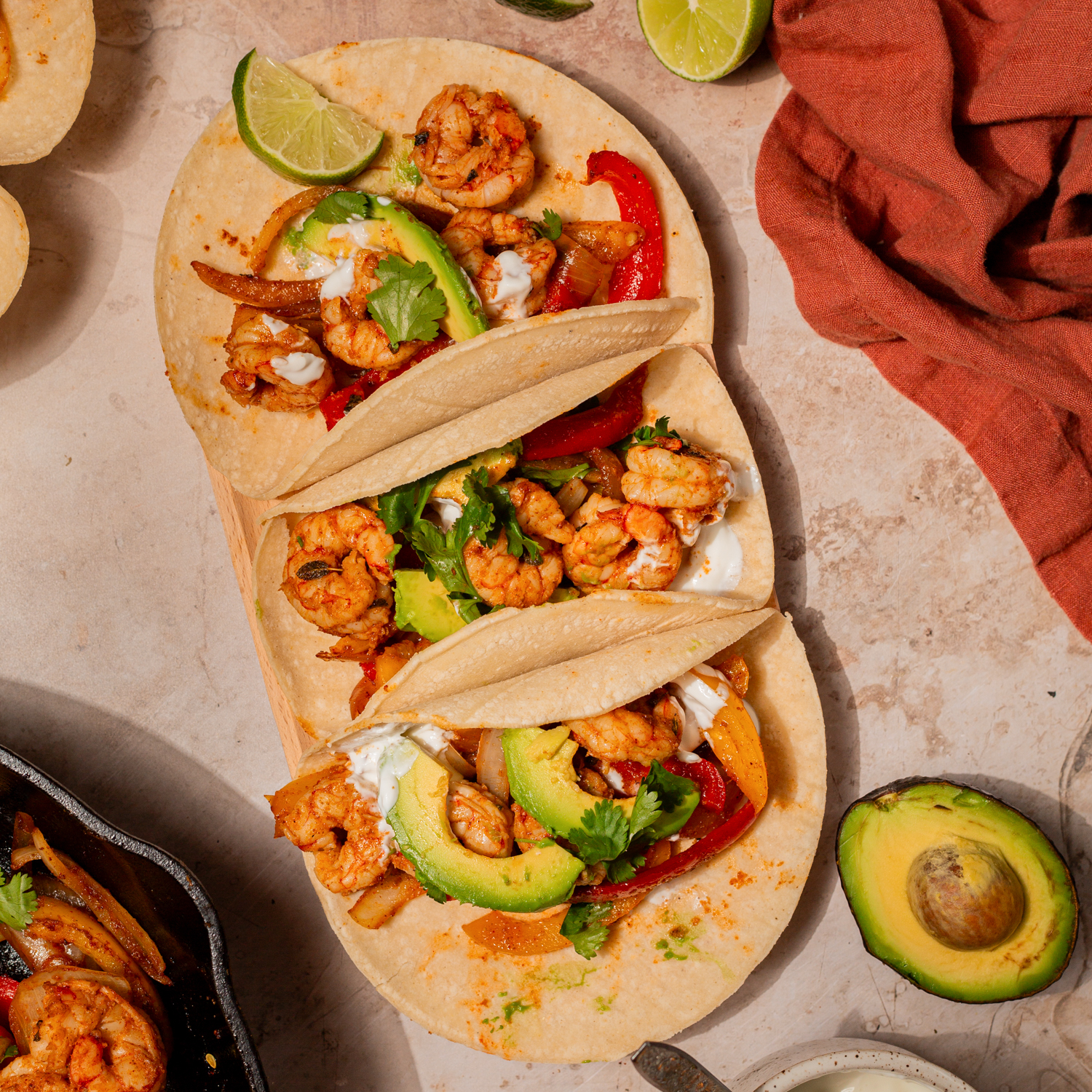 Seasoned shrimp in tortillas topped with sliced avocado.