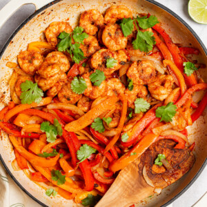 Seasoned shrimp and peppers cooked in a large pan.